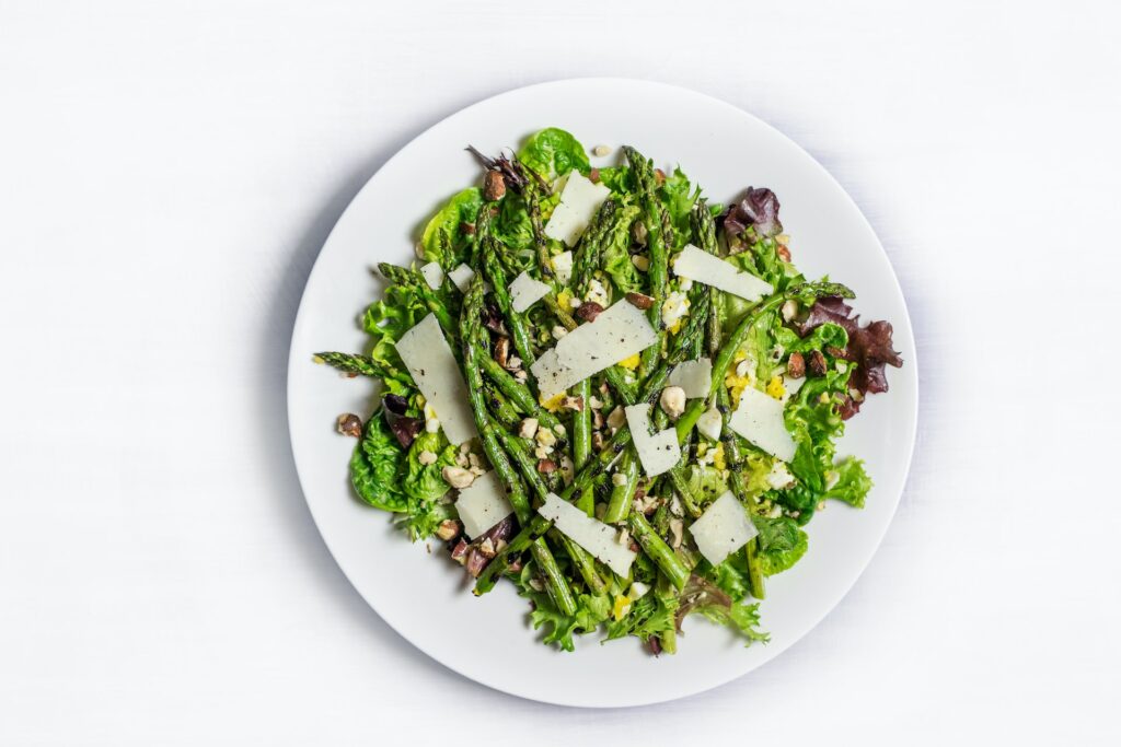 绿色Asparagus与压碎坚果和菜菜白板上白表